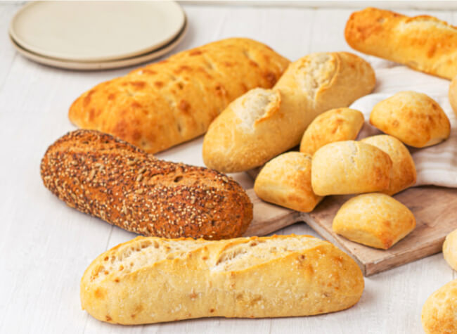 Different types of breads and rolls assorted on a cutting board