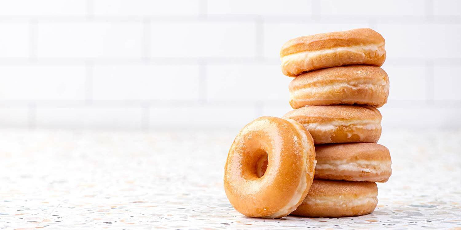 Glazed donuts stacked on top of each other with one leaning to the side