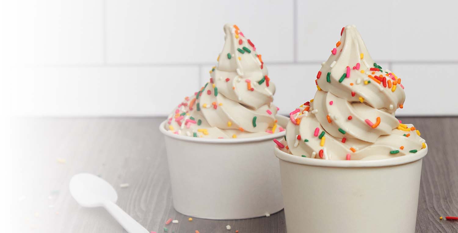 Two cups filled with soft serve ice cream topped with multicolored sprinkles