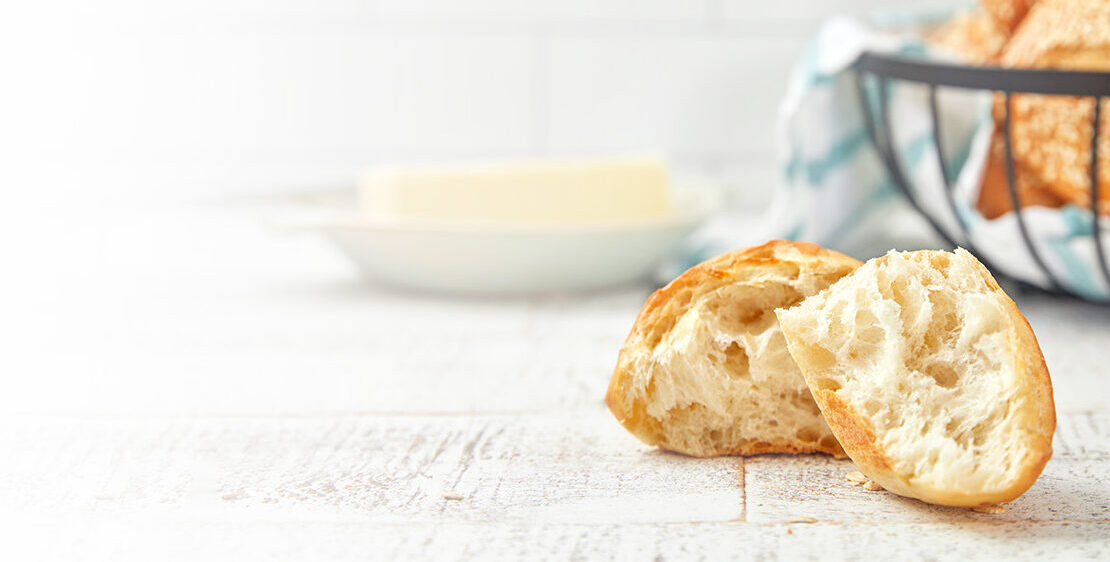 A basket of rolls with one roll cut showing the inside in the foreground