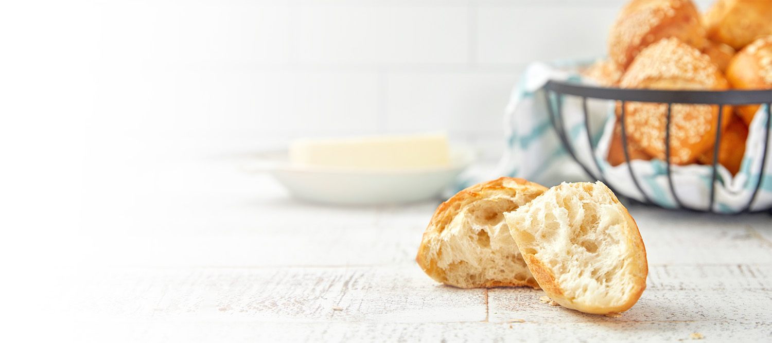 A basket of rolls with one roll cut showing the inside in the foreground