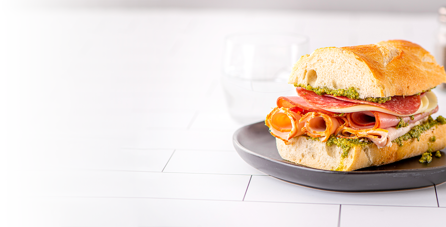 Sandwich with meats, cheese, and a spread on a plate