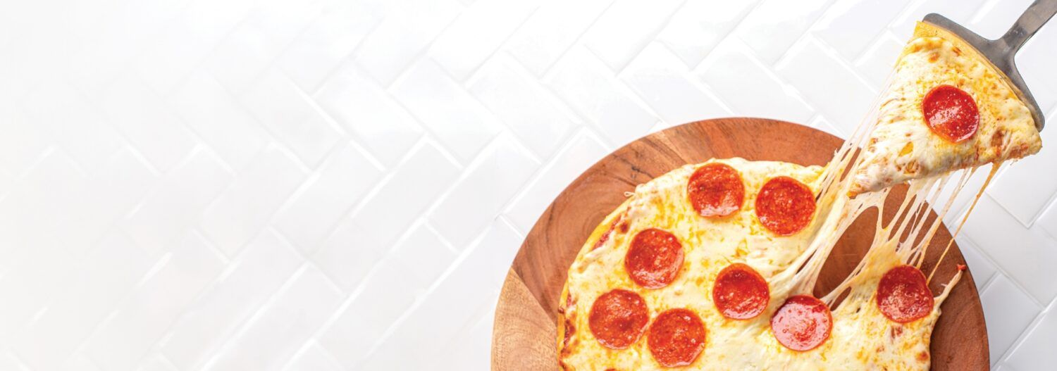 slice of cheese pizza with pepperoni being pulled away from the full pizza pie