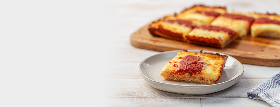 Multiple slices of pizza on a cutting board with one slice on a plate
