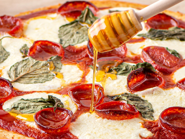hot honey being drizzled on a pizza