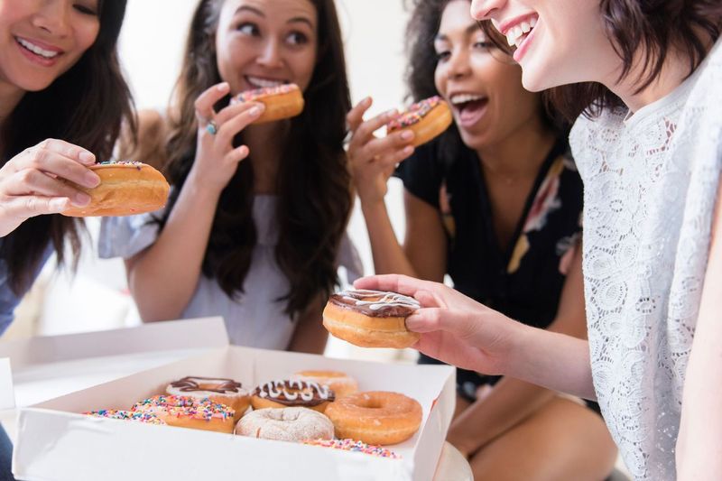 young adults eating donuts